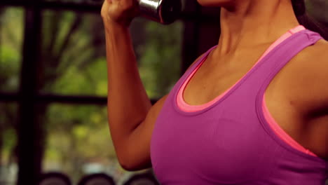 una mujer súper en forma levantando pesas.
