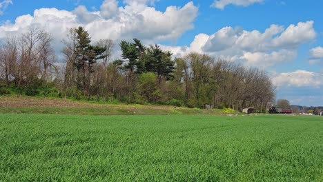 view of a steam passenger train approaching blowing smoke and steam on a beautiful spring day