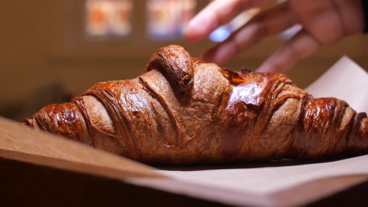 Mano che prende e appoggia un croissant appena sfornato