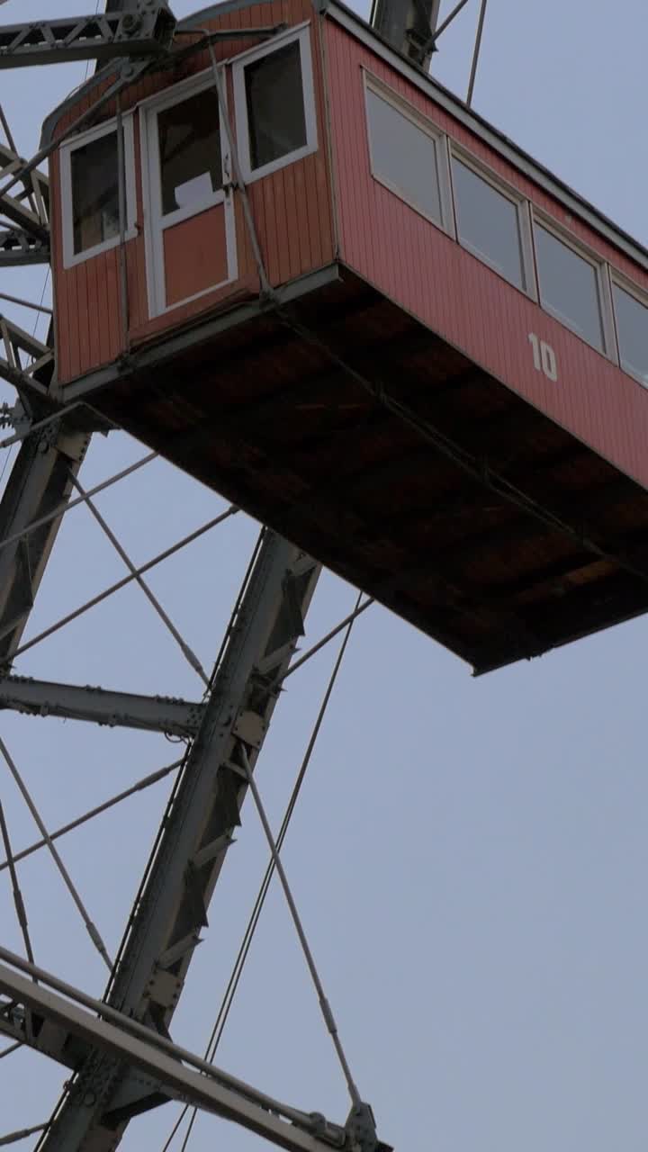 Cabina rossa di ruota panoramica in lenta rotazione contro un cielo grigio