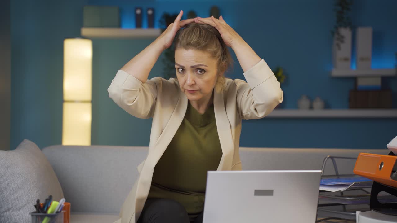 женщина, работающая в домашнем офисе, смотрит в камеру с счастливым и улыбающимся лицом.