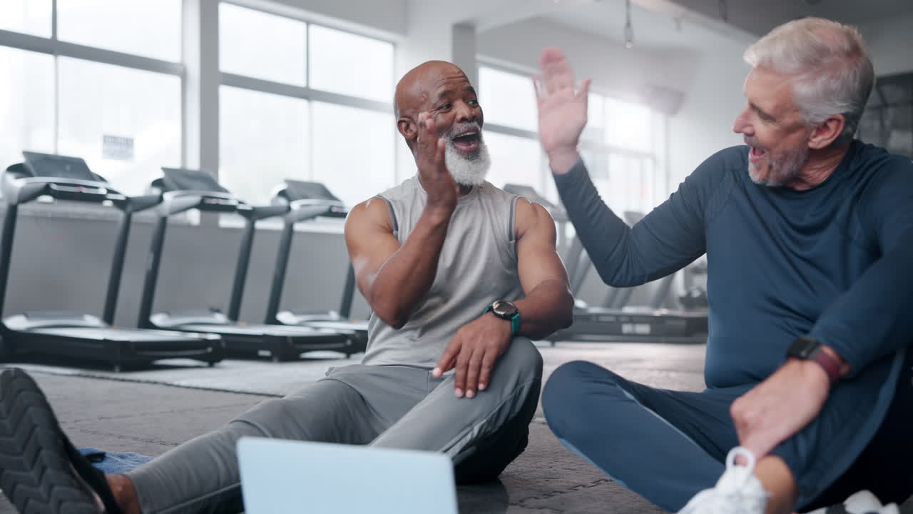 Senior men taking a break and laughing at the gym