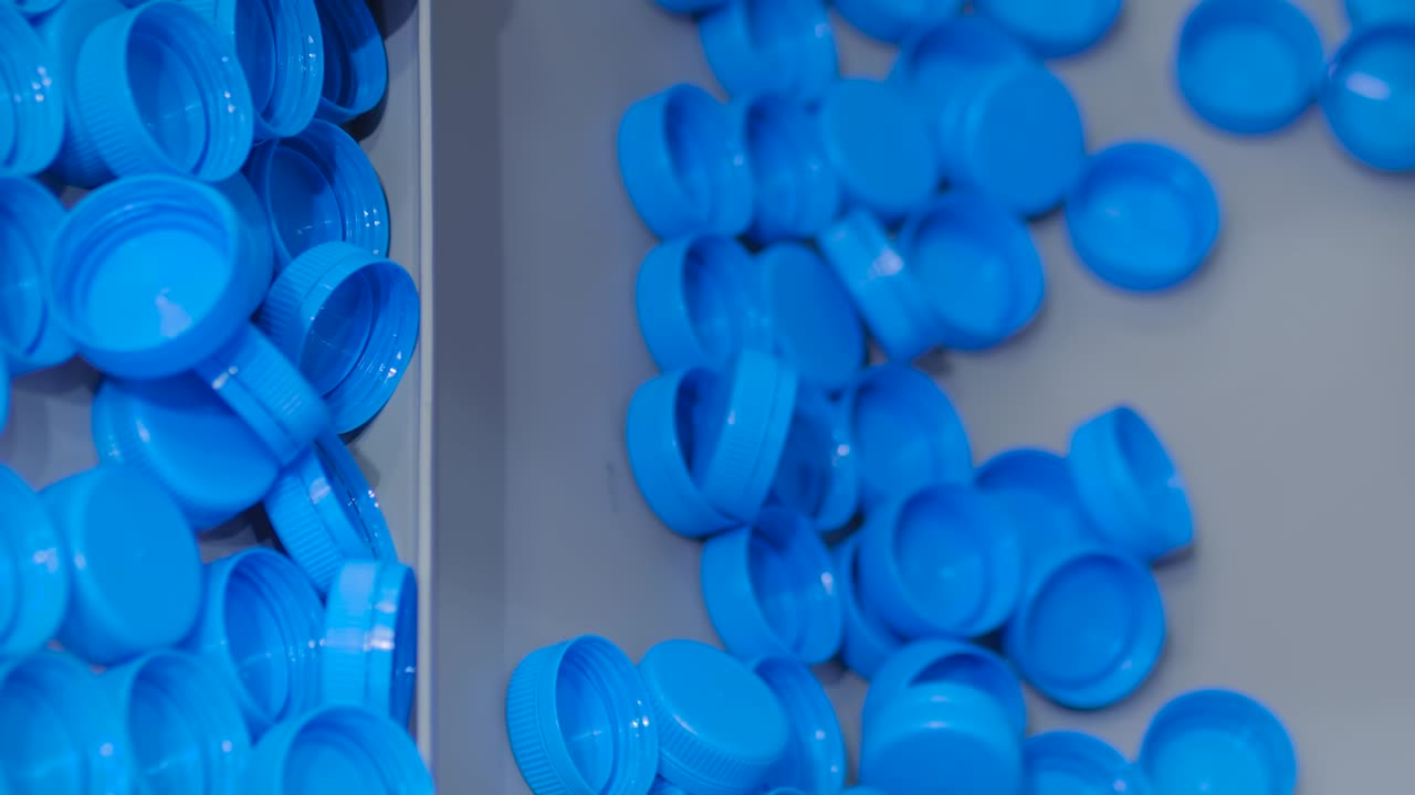 Many blue plastic bottle caps moving on conveyor belt - production line