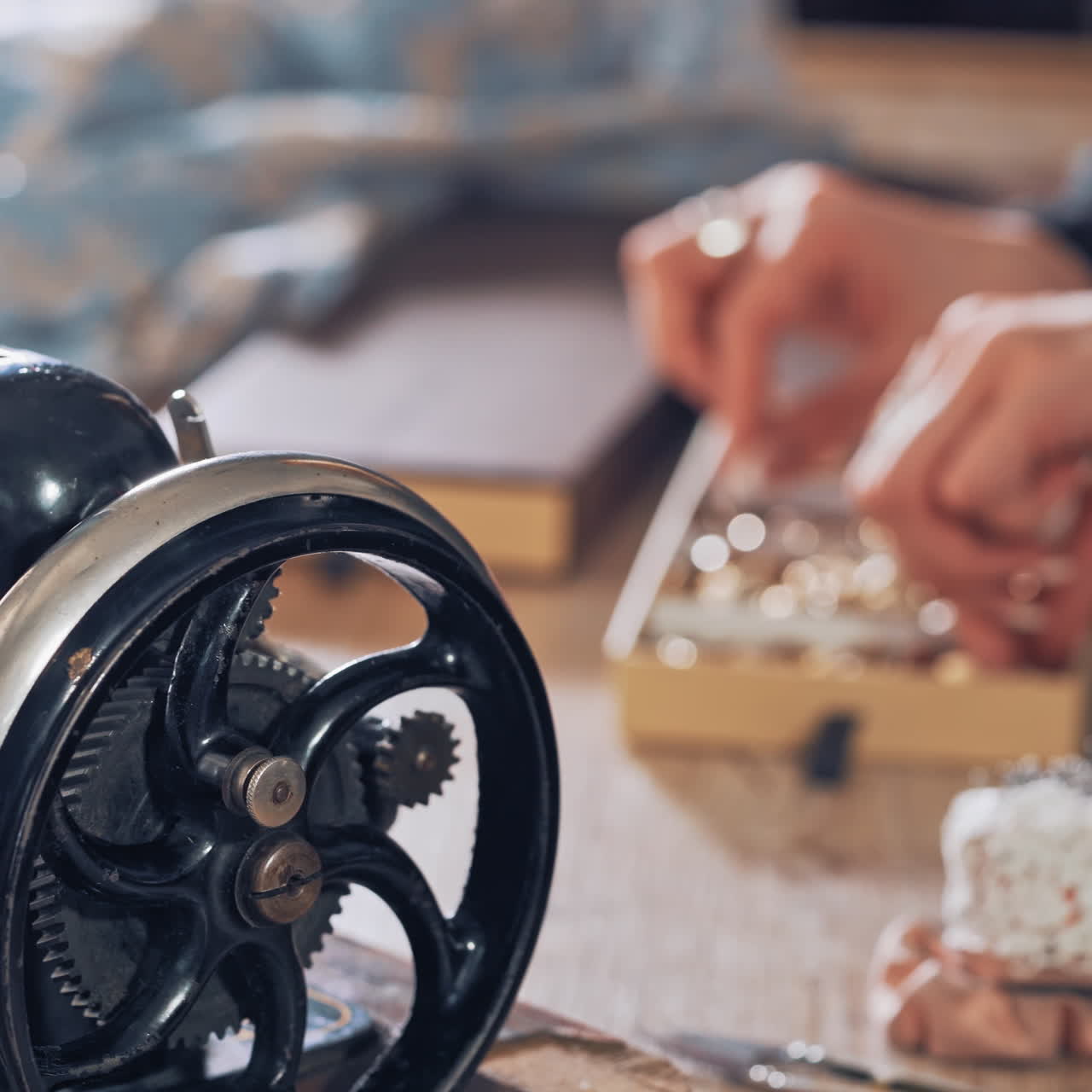 Handmade sewing machine on the table on the background of tailor's hands in workplace. Old black sewing machine and a seamstress nearby in atelier. Retro sewing machine.