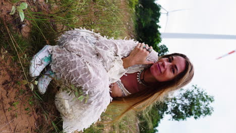 happy young attractive woman with long healthy hair looking to camera with windmills in background