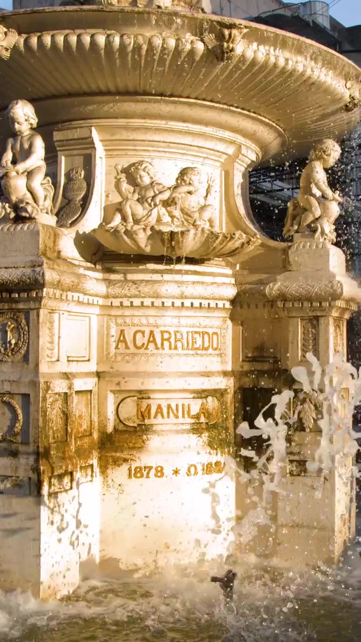 Primo piano della fontana in pietra ornata Carriedo con spruzzi d'acqua sotto la luce solare intensa.