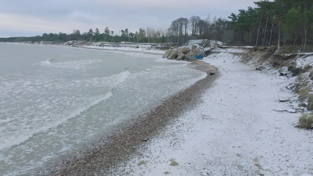 вид с воздуха на заброшенные приморские фортификационные сооружения в северных фортах каросты на берегу балтийского моря, пасмурный зимний день, широкая съемка с беспилотника, движущегося низко вперед