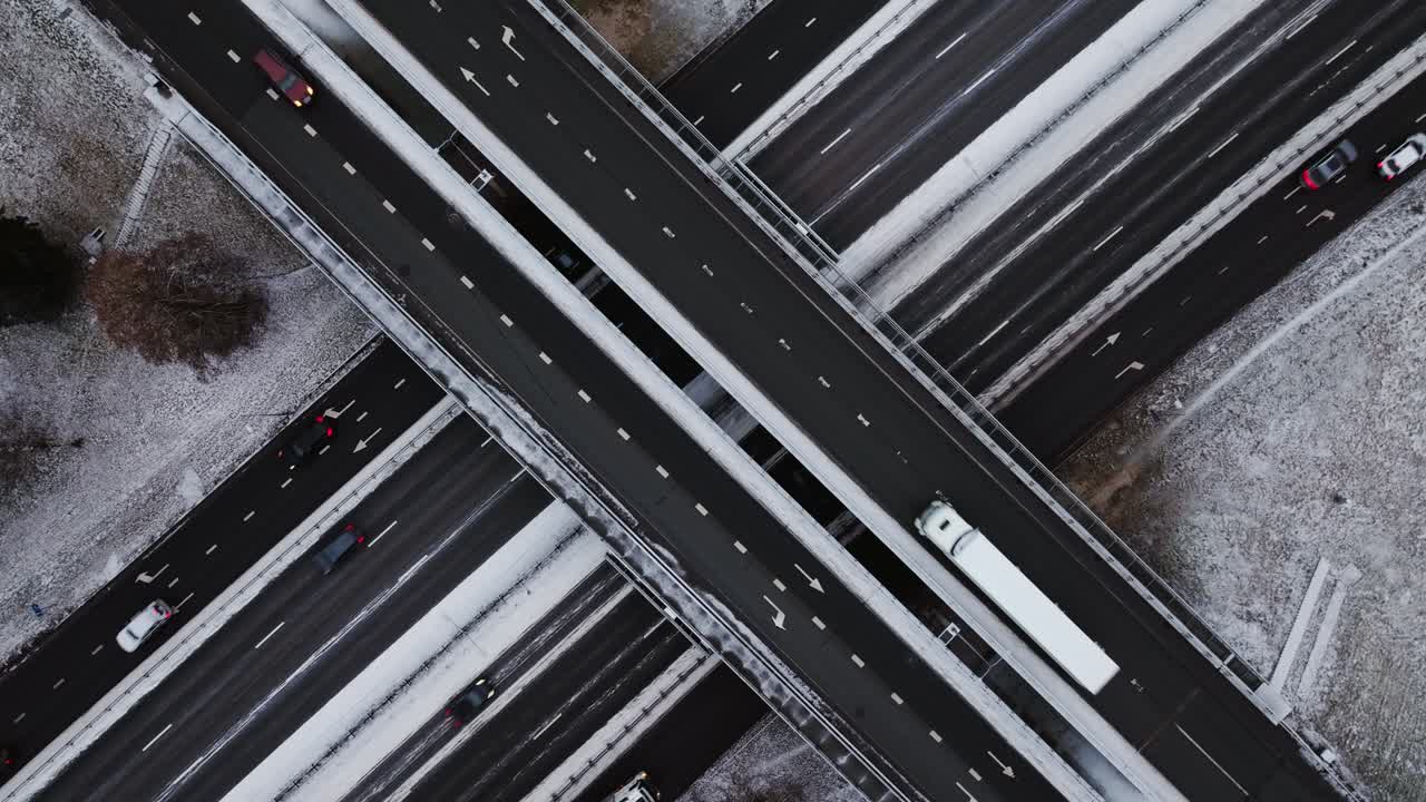 Overhead view of snowy highway interchange with vehicles moving in winter, DRONE
