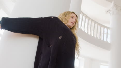 focused blonde woman in black long sleeve loose pullover performing a contemporary dance in the studio