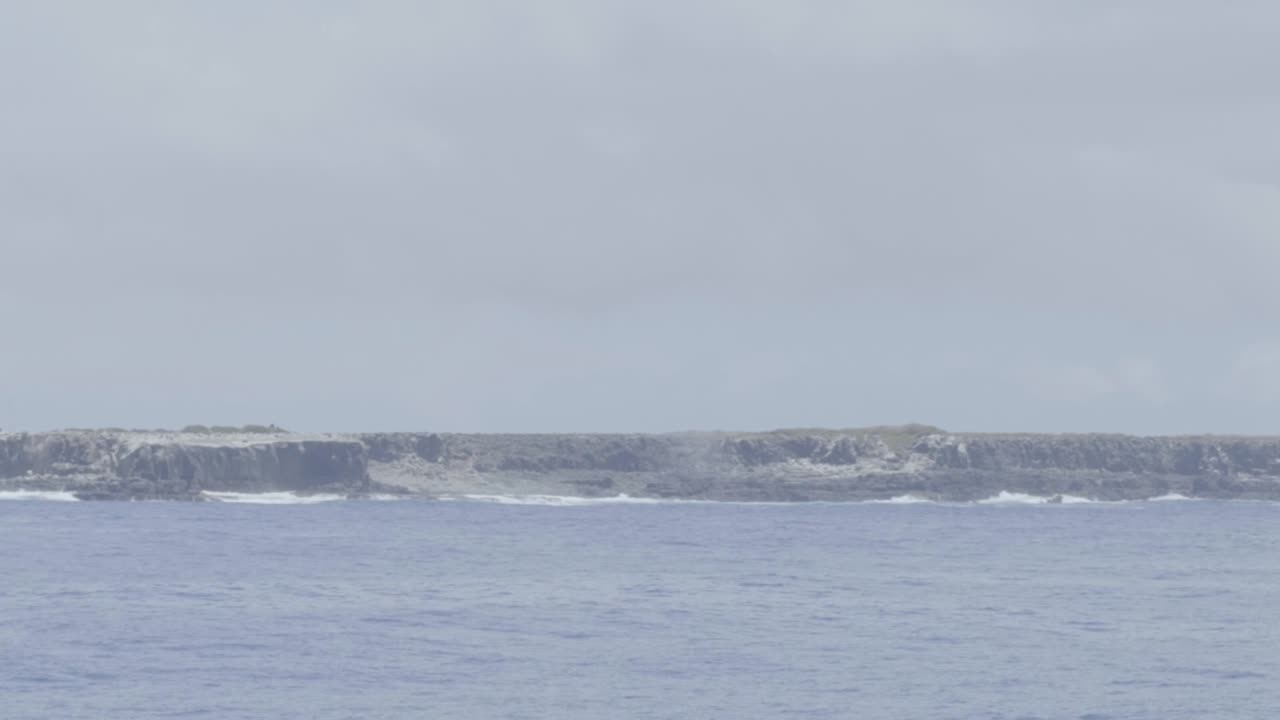 Espanola island in the Galapagos Islands. Shot from moving cruise. Waves crash into the massive rocks of the land.