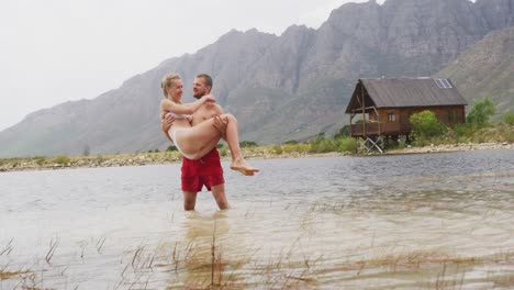 caucasian couple having a good time on a trip to the mountains, wearing bathing suits and standing i