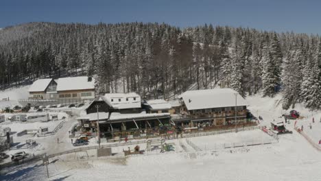 Edificio-Principal-Del-Complejo-De-Deportes-De-Invierno-De-Kope-En-Las-Montañas-Pohorje-Con-Fuertes-Nevadas,-Toma-De-Pedestal-Aéreo