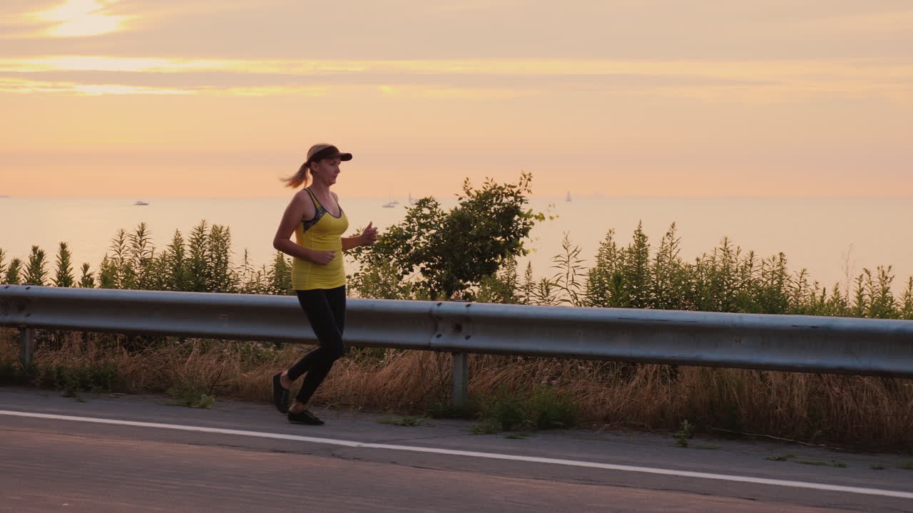 mujer hace un trote nocturno a lo largo de la carretera a lo largo del lago steadicam seguir tiro