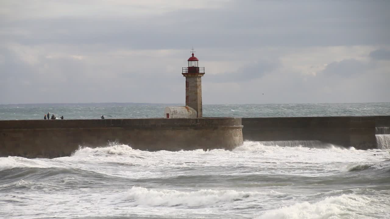 las olas aplastan el faro de oporto en una noche nublada y ventosa