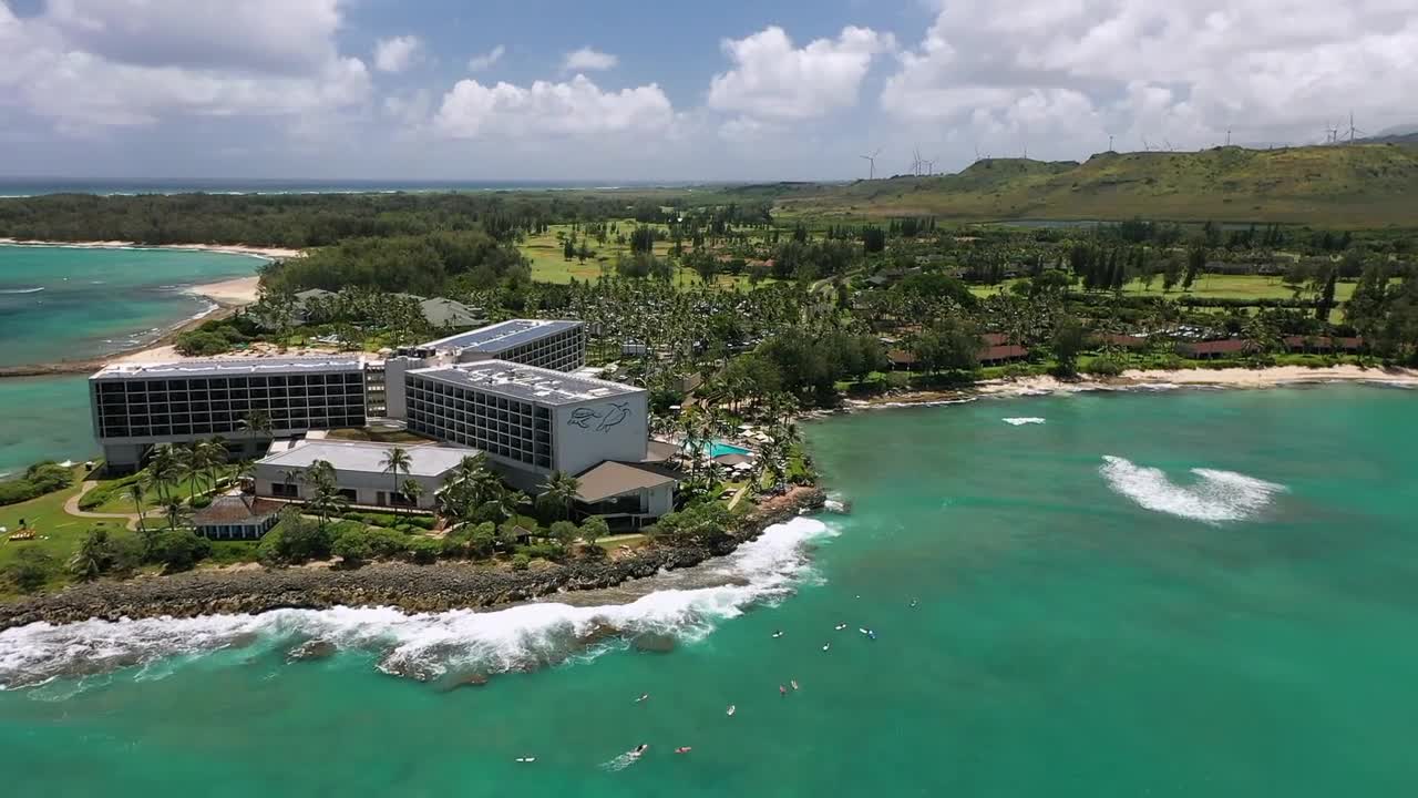 Aerial drone footage of a luxury oceanfront resort in Hawaii surrounded by turquoise waters, palm trees, and white sand beaches. A breathtaking tropical paradise showcasing the beauty of island life