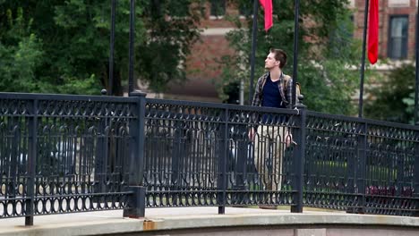 stunning young man walks across bridge with his