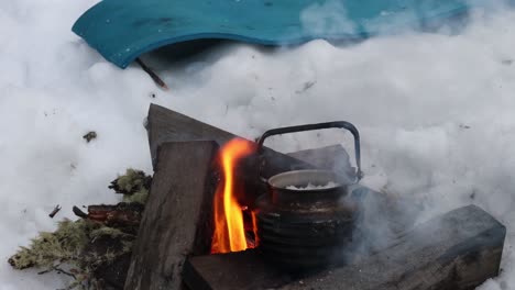 a traditional australian billy boiling water over a fire in the snow of australias alpine region