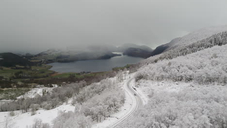 coche conduciendo por la nevada carretera nacional noruega 13 con el fiordo al fondo en un día nublado, noruega