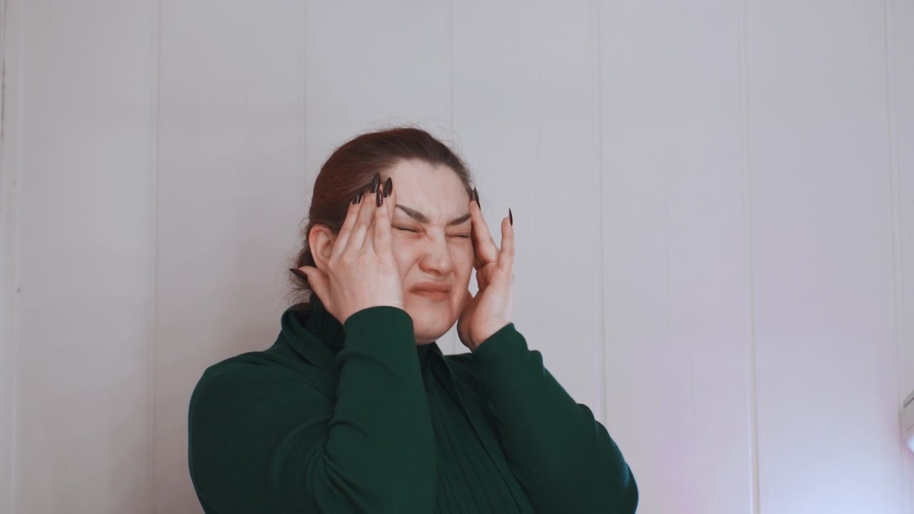 Donna che si massaggia le tempie per trovare sollievo. Un rituale auto-lenitivo che prevede un delicato massaggio alle tempie e un ambiente tranquillo. Un ambiente sereno dove la donna si massaggia delicatamente le tempie per alleviare il mal di testa.