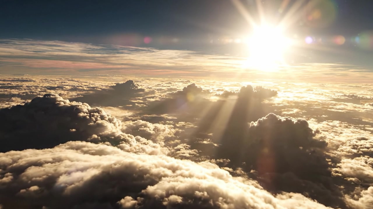 Vista aerea mozzafiato di nuvole soffici immerse nella luce dorata del sole, con raggi luminosi che trafiggono il cielo nuvoloso, catturando un momento sereno della bellezza della natura.