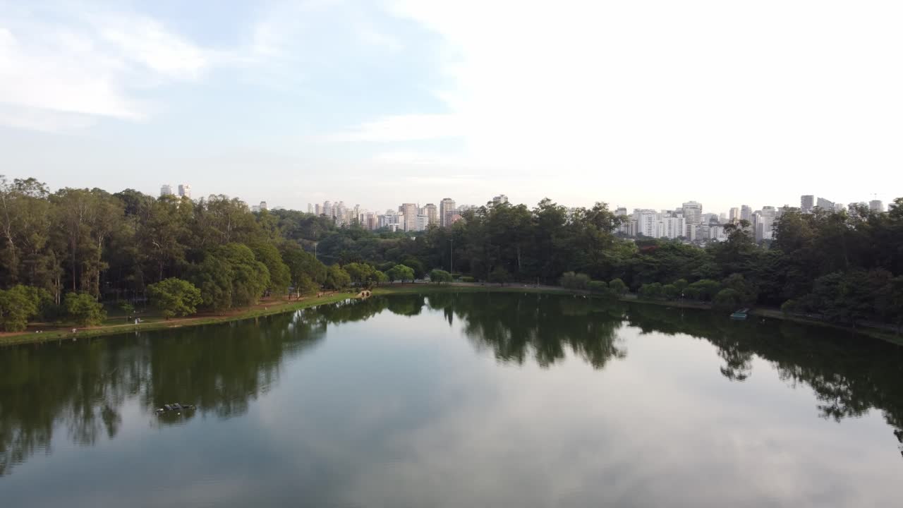 Aerial view of ibira lake with Sao Paulo skyline cityscape, drone fly above the lake revealing the modern metropolitan skyline