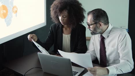 bebaarde baas in gesprek met jonge afro-amerikaanse assistent