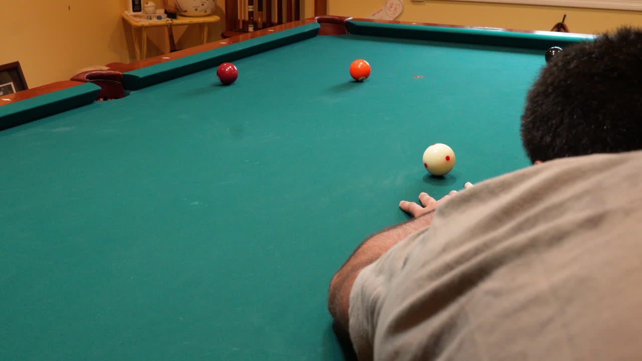 Man Playing 8 Ball Pool Shoots Solid Orange 5 Ball into Corner Pocket on a Brunswick Table with Green Felt and Two Balls on the Table, Open Bridge Hand and Wooden Cue Stick, No Faces Perspective Angle