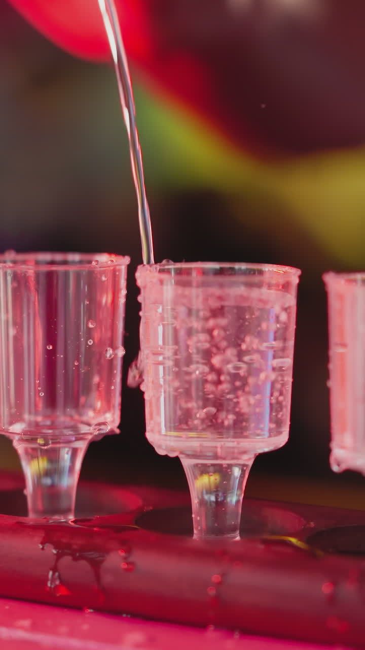 el camarero vierte la bebida alcohólica en vasos pequeños en el mostrador de primer plano. el camarero prepara un juego de tiros para los invitados en el club nocturno. el barman sirve una bebida fuerte