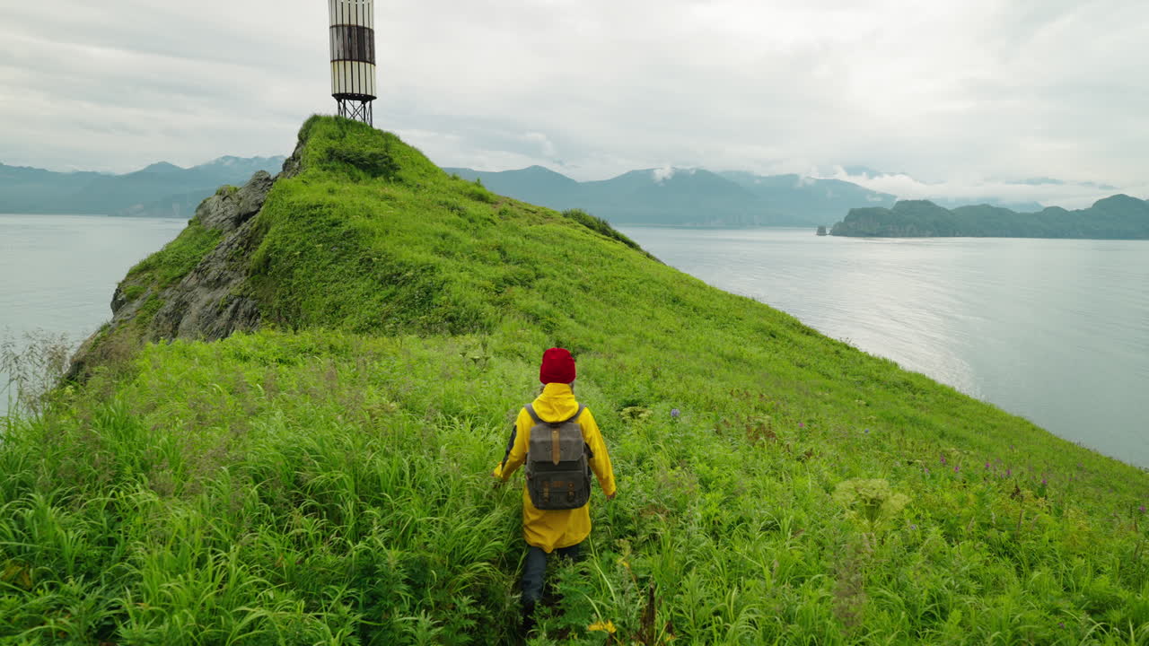Hiker on a grassy hilltop overlooking a bay