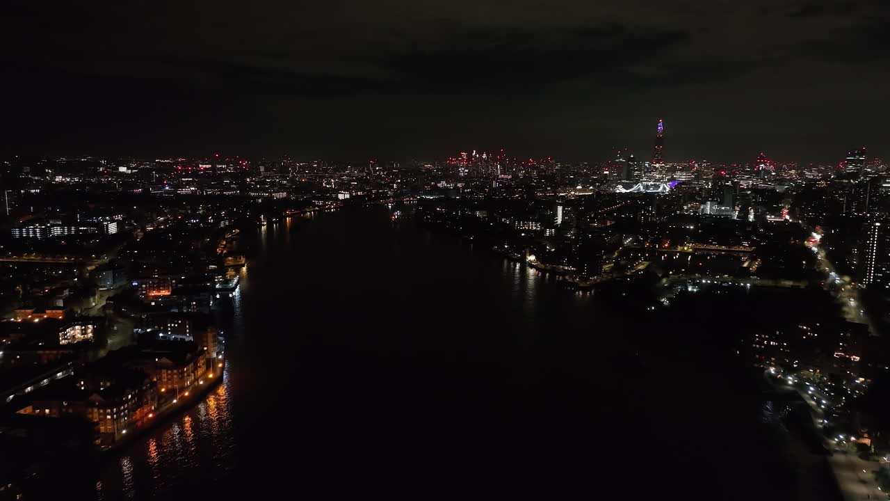 Aerial view following the Thames river toward downtown London, night in England