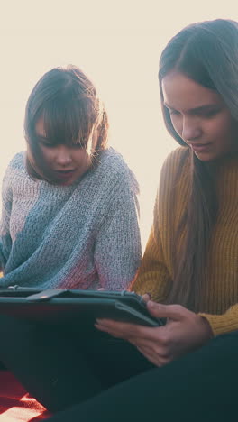 beautiful women with tablet and laptop in comfortable campsite with tent against sunset light in autumn evening