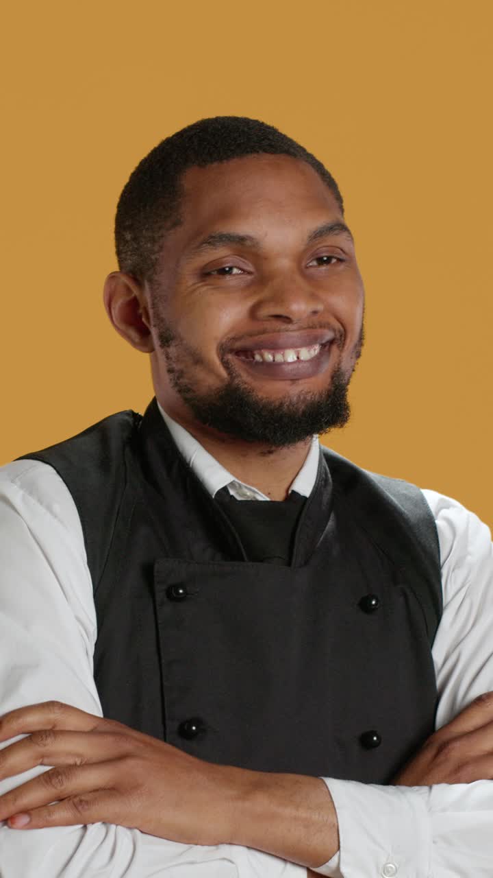 Chef afroamericano sorridente che posa con le braccia incrociate