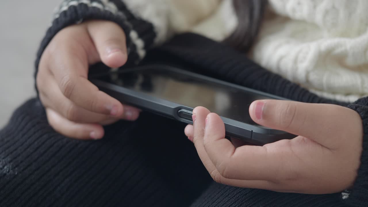 Close-up of Child's Hands Holding and Using a Smartphone