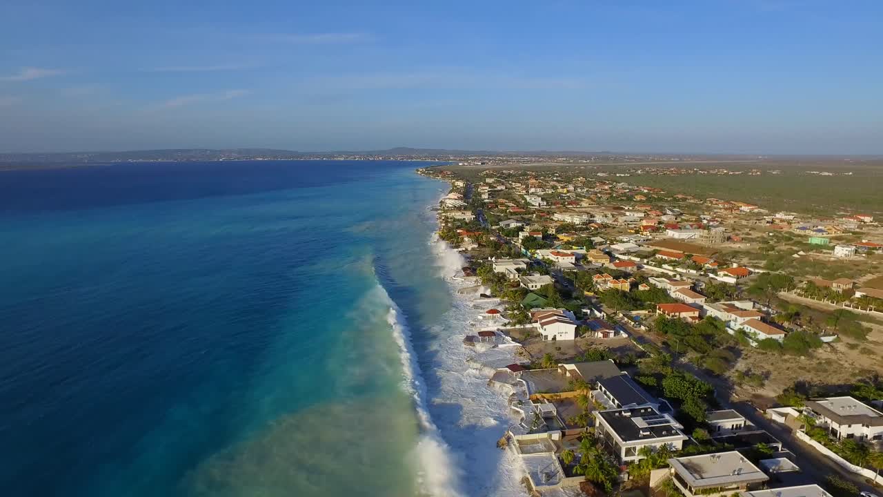 Aerial view of a coastline with houses and waves