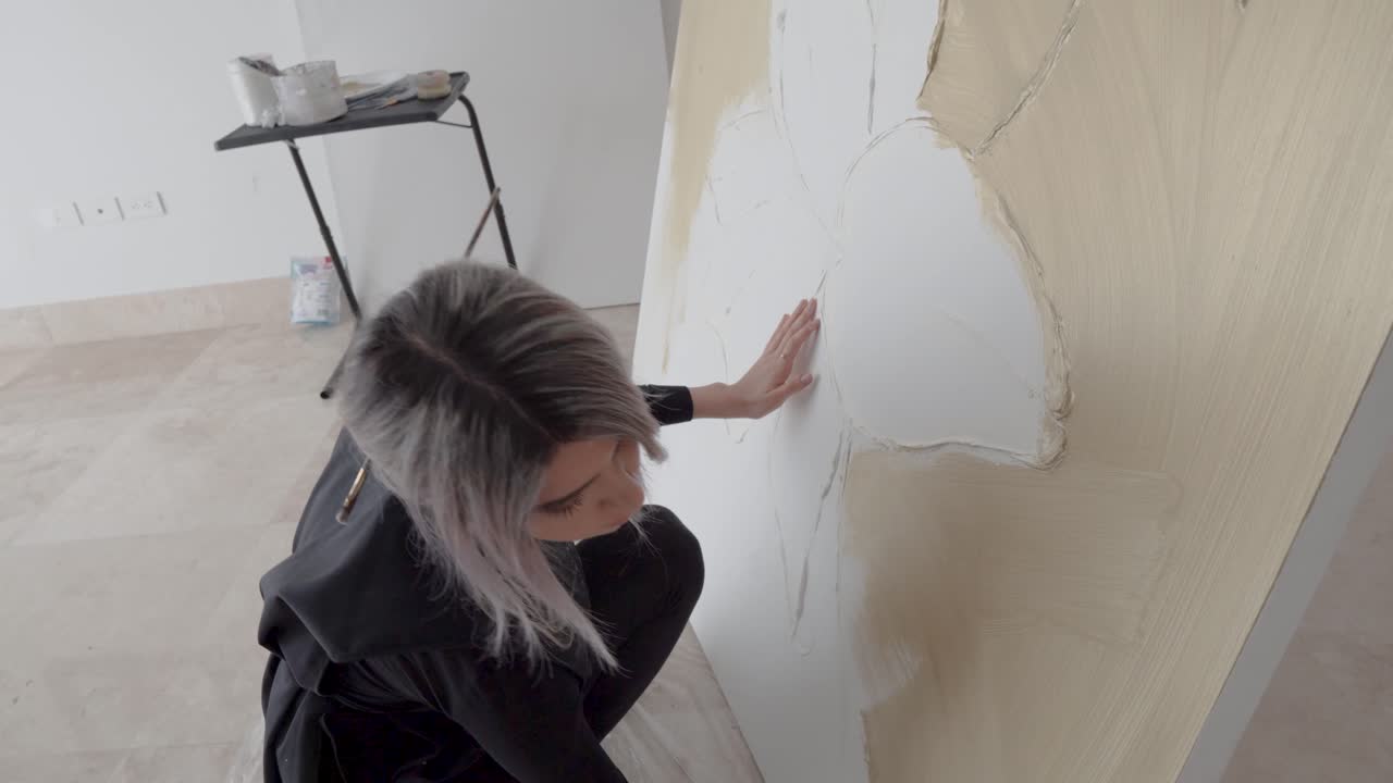 Artista seduto davanti a una grande tela che lavora con un grande pennello in uno studio d'arte.
