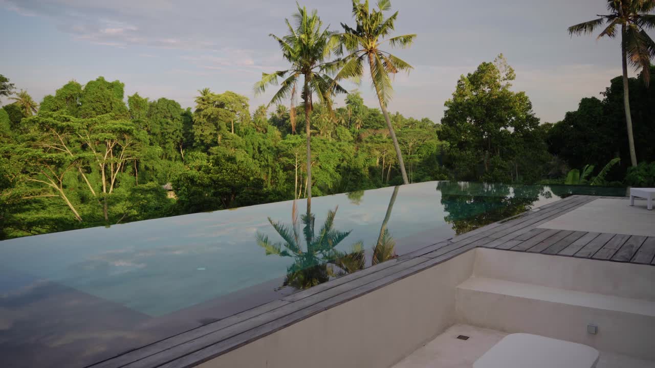 Tropical sunken lounge with wooden planks, blending natural elements and modern design on an infinity pool surrounded by lush jungle greenery and peacful views in the heart of Ubud, Bali.