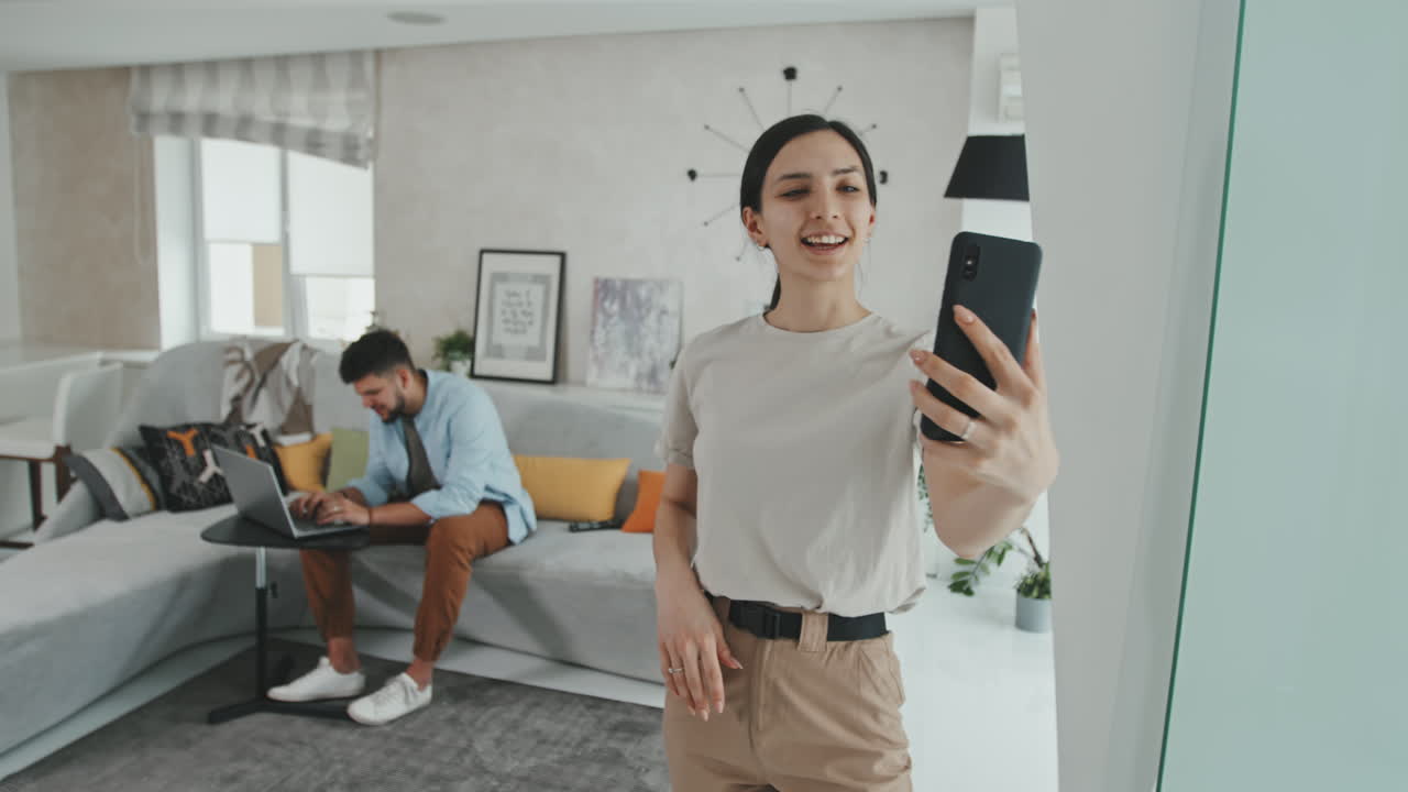 Young Married Couple Video Calling On Smartphone At Home