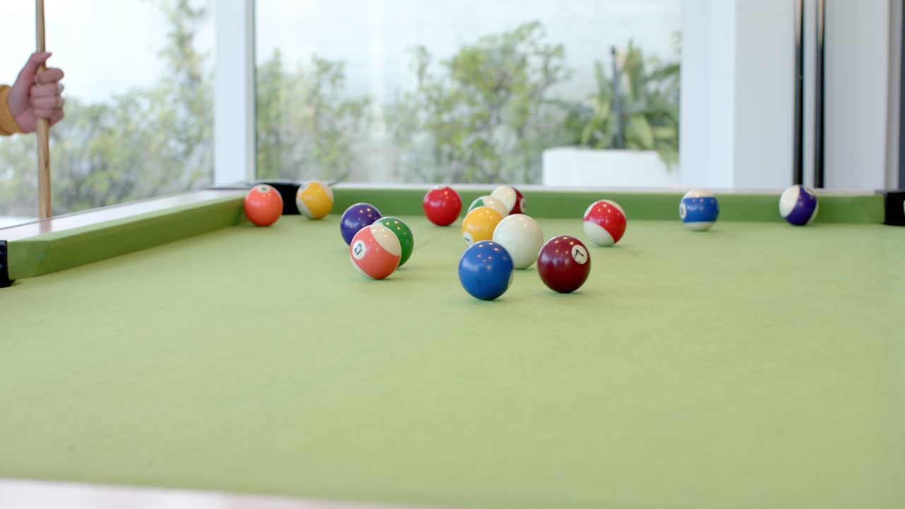 Player is placing cue ball, aligning stick and striking to break colored balls on pool table
