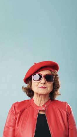 portrait of a stylish senior woman in a red beret and sunglasses