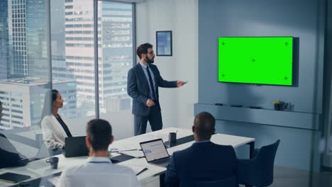 office conference room meeting presentation: businessman talks, uses green screen chroma key wall tv. successfully presenting a product to group of multi-ethnic investors. e-commerce strategy
