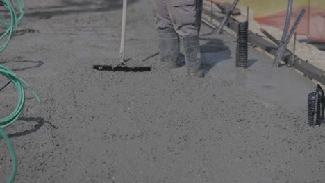worker spreading mix of cement and concrete at a construction site, levelling floors