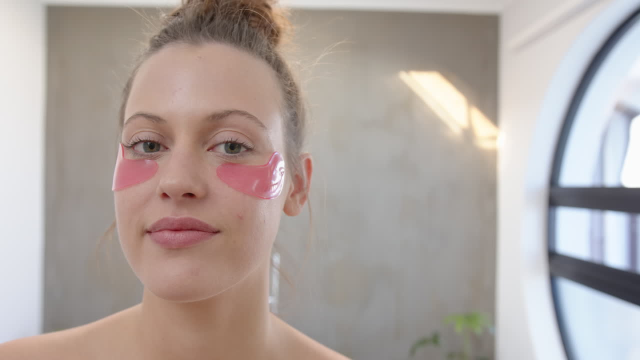 Applying under-eye patches, young woman enjoying spa treatment at home
