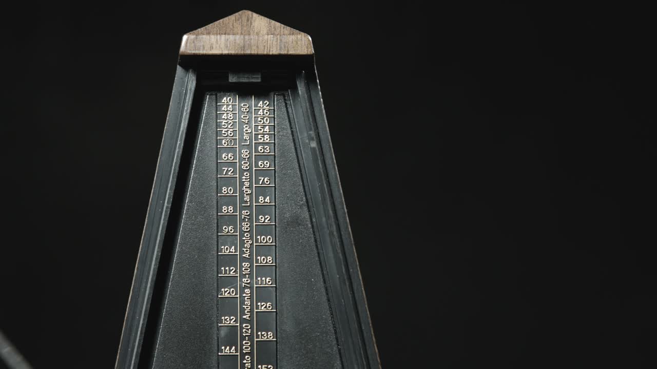 un primer plano de un metrónomo antiguo con un péndulo dorado