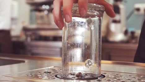 bar tender washing glass with glass washer at bar counter