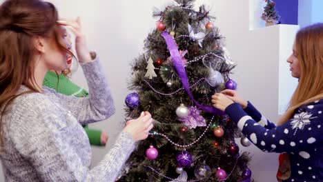 tres chicas decorando un árbol de navidad y hablando
