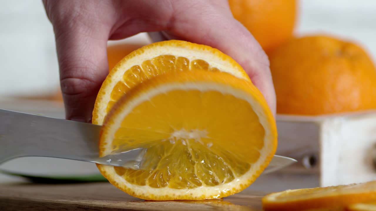 manos masculinas cortando naranjas frescas en rebanadas redondas.