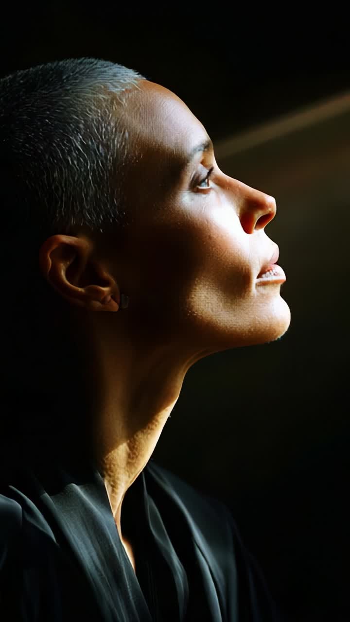 A Serene Portrait of a Woman with Short Hair Gaze Upward in Contemplation, Bathed in Soft Light, Capturing the Essence of Peace and Introspection in a Dark Setting