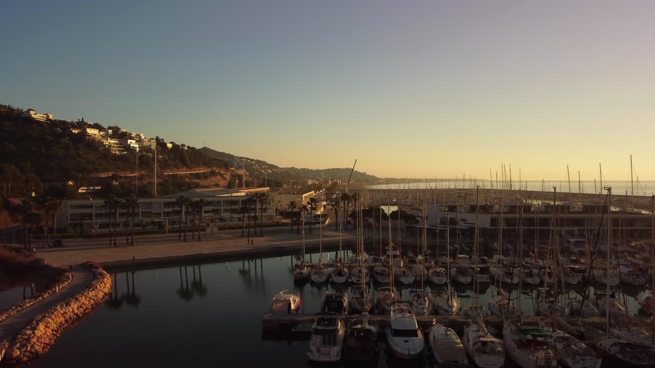 바르셀로나의 포트 기네스타에서 해가 뜨고, 평온한 항구에 정박한 배들이