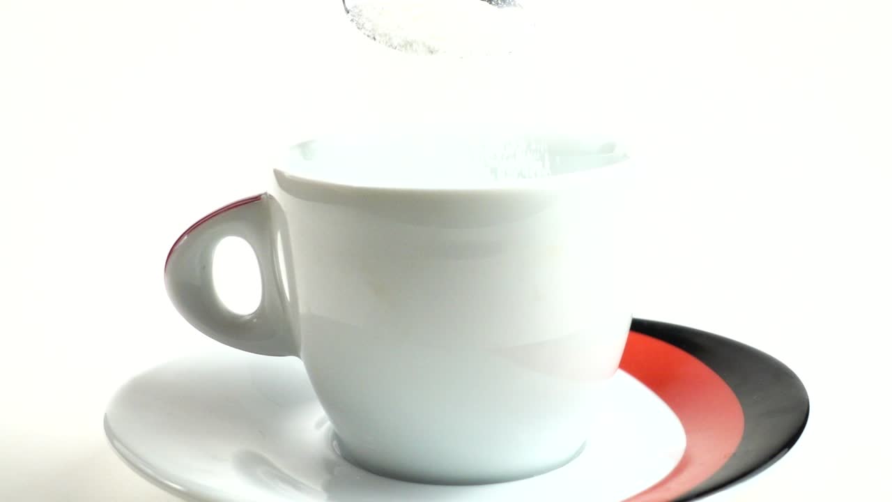 Dalla cucchiaio lo zucchero viene versato in una tazza. Movimento lento