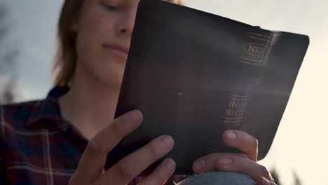 Close-up-of-a-girl-reading-The-Bible-in-a-forest-on-a-sunny-day